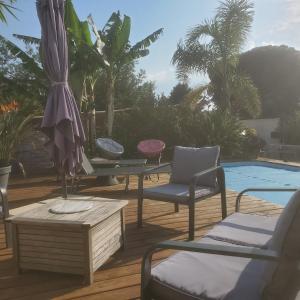 patio z krzesłami i parasolem przy basenie w obiekcie Madinina w mieście Bormes-les-Mimosas