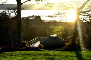 Kelburn Yurts في Fairlie: وجود قارب جالس على العشب بجانب جسر