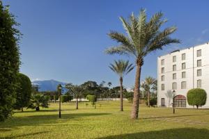 a park with palm trees in front of a building at Bisila Palace in Ciudad de Malabo