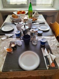 una mesa con platos y utensilios blancos. en le stanze di Saraswati, en Salorno