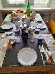 a table with white plates and utensils on it at le stanze di Saraswati in Salorno sulla Strada del Vino