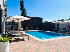 a swimming pool with two umbrellas and chairs and a pool at Panorama Boutique Guest House in Graskop