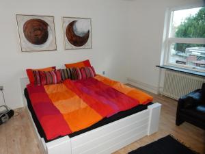 a bedroom with a bed with a colorful blanket on it at Kummelefort in Kruså