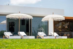 two umbrellas and lounge chairs in front of a building at Cresto Iconic Villa, with Heated Spa Whirlpool, By ThinkVilla in Angeliana