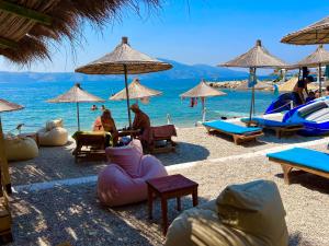 a beach with chairs and umbrellas and the water at Hotel Divers in Vlorë