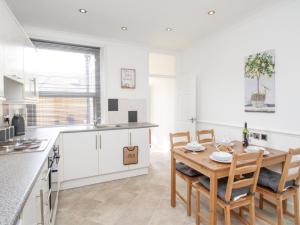 uma cozinha e sala de jantar com uma mesa de madeira e cadeiras em Stones Throw em Weymouth