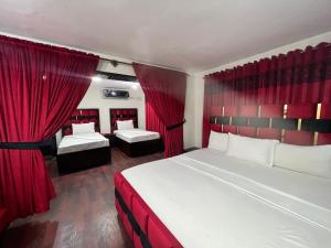 a bedroom with two beds and red curtains at Al Atif Guest House in Islamabad