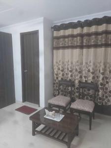 a living room with two chairs and a table and a window at OYO Singh Homestay in New Delhi