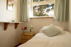 a bedroom with a white bed and a window at 3 Linkside, Thurlestone, South Devon, family home close to the beach in Thurlestone