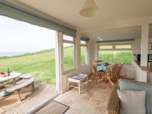 a living room with a table and chairs and a large window at Siesta Chalet in Bridport