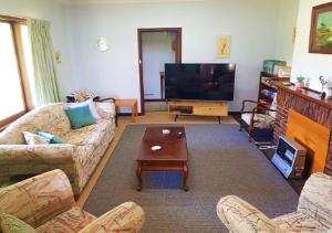 ein Wohnzimmer mit einem Sofa und einem TV in der Unterkunft Warradale Lodge and Mini Golf 