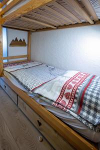 a bed in a wooden bunk bed with a quilt on it at Aux pieds des pistes, Les 2 Alpes in Vénosc