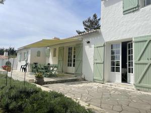 a white house with green doors and a patio at Maison Noirmoutier-en-l'Île, 5 pièces, 8 personnes - FR-1-224B-477 in Noirmoutier-en-l'lle