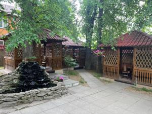 un jardin avec deux kiosques en bois et une fontaine dans l'établissement Grand Hotel, à Mohyliv-Podilʼsʼkyy