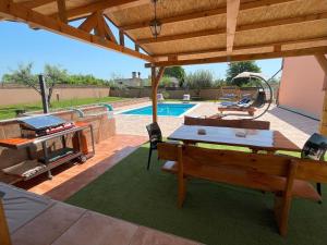 a patio with a table and a grill and a pool at Villa Rosa Apartman in Loborika