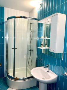 a blue tiled bathroom with a shower and a sink at Vespera Apartments in Bol