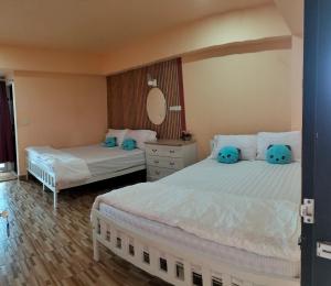 two beds in a hotel room with blue pillows at P Place พีเพลส ห้องพักรายวัน in Bangkok