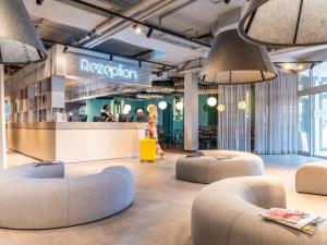 un hall avec des canapés et des chaises dans un bâtiment dans l'établissement ibis Styles Graz Messe, à Graz