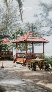 - un kiosque en bois avec une table de pique-nique au bord de l'eau dans l'établissement Pantai Camara Homestay, à Rorahmakan