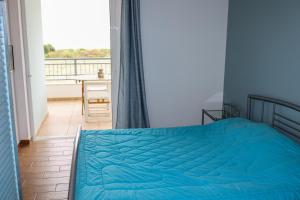 a bedroom with a blue bed and a balcony at Agrilis Home in Filiatra