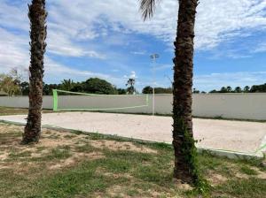 a tennis court with two palm trees and a volleyball net at Ap Remanso - Cond Lençois Confort Barreirinhas in Barreirinhas +29 photos