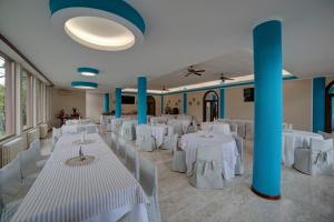 ヴァストにあるHotel Sportingの白いテーブルと椅子、青い柱が並ぶ宴会場