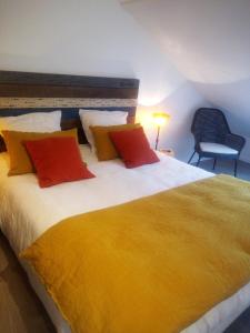 een slaapkamer met een groot bed met gele en rode kussens bij Les Marines du Treustel in Combrit