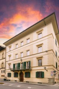 a large white building with green windows and a sky at Donna Lipsi - La Dimora degli Affreschi Florence in Florence