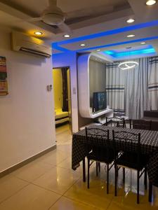 uma sala de jantar com mesas e cadeiras pretas e uma televisão em Cozy Homestay Cyber City 3BR Near KKIA 10 minutes KK Centre wifi 30mps astro channel em Kapayan