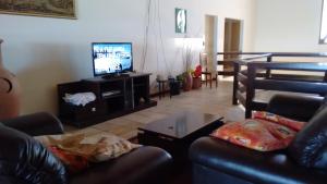 a living room with a couch and a television at Pousada Mirante in Conceição da Barra