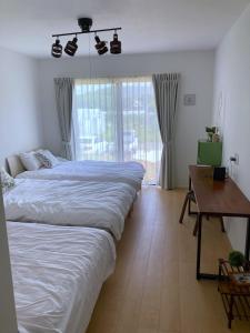 1 dormitorio con 2 camas, mesa y escritorio en Nakijin Resort Guest House, en Nakijin