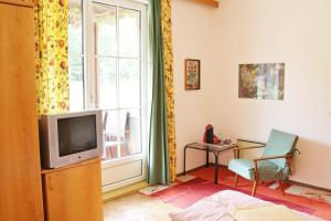 a bedroom with a television and a chair and a window at Familienparadies Reichenhauser in Keutschach am See