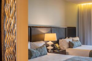 ein Hotelzimmer mit 2 Betten und einer Lampe in der Unterkunft Crocs Resort & Casino in Jacó
