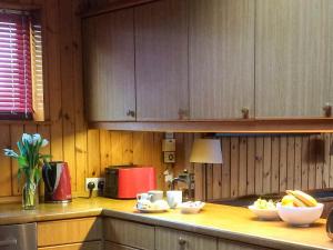 a kitchen with wooden cabinets and bowls of fruit on a counter at Seaview Cottage - 27991 in Dunure