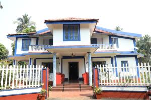 una casa azul y blanca con una valla blanca en Dona Sa Maria Eco Hotel, en Cavelossim