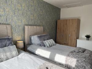 a bedroom with two beds and a wall with wallpaper at Modernised central Wigan townhouse sleeps up to 6 in Wigan