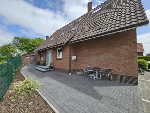 a brick house with chairs and a patio at Mienhus Apartments Ferienwohnung Boppo Mienhus in Norden