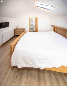 a bedroom with a large white bed and wooden floors at Stunning stone coach house in Marple