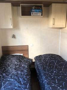 two beds in a small room with blue sheets at mobilhome 582 Les Charmettes 3ch tout équipé in Les Mathes