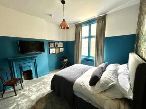 a blue bedroom with a bed and a fireplace at The Crown Rooms in London