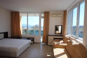 a bedroom with a bed and a couch and windows at Menada Apartments in Sunny Beach in Sunny Beach