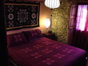 1 dormitorio con cama morada y pared de piedra en Casa Rural Petita d'en Chinascas, en Vespellà