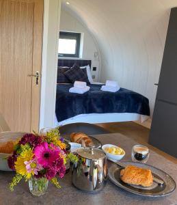 Cette chambre comprend un lit et une table avec du pain et des fleurs. dans l'établissement Raven's Gully - Brodick, Isle Of Arran, à Brodick