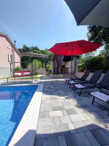 a pool with two chairs and a red umbrella at Apartment Vetva in Nedeščina