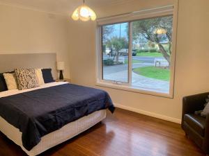 a bedroom with a bed and a large window at Location, Location, Location! Walk to beach & town in Mornington