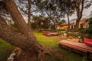 une cour avec un arbre, un canapé et des tables dans l'établissement Villa Maria Affittacamere, à Canicattini Bagni