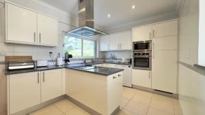 een keuken met witte kasten, een gootsteen en een raam bij Burgau Sea View, Beach & Pool Villa in Budens