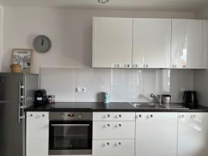 een keuken met witte kasten en een klok aan de muur bij Kapart City in Rzeszów