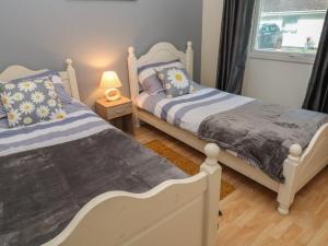 two twin beds in a room with a window at 11 Tremore in Liskeard