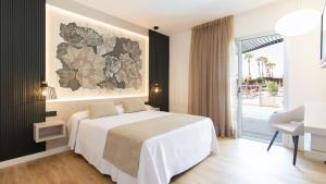 Un dormitorio con una cama blanca y una ventana grande. en Golden Taurus Aquapark Resort, en Pineda de Mar